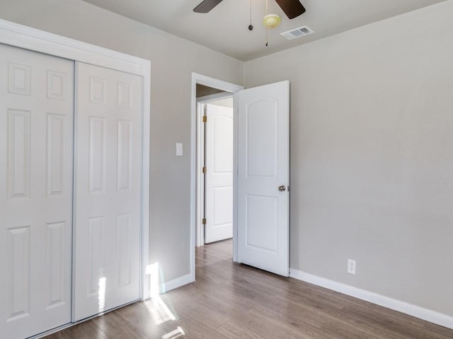 unfurnished bedroom with ceiling fan, a closet, and hardwood / wood-style floors