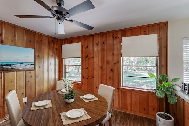 dining room featuring wood walls, ceiling fan, dark hardwood / wood-style floors, and a healthy amount of sunlight