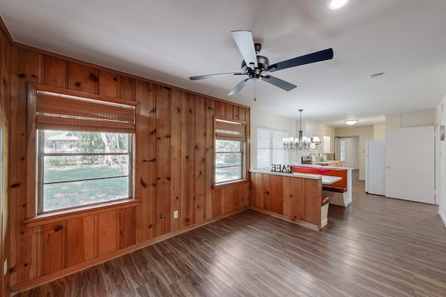 kitchen featuring white refrigerator, wood walls, kitchen peninsula, dark hardwood / wood-style floors, and ceiling fan with notable chandelier