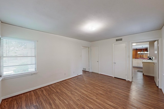 unfurnished bedroom with an inviting chandelier, dark hardwood / wood-style floors, and sink