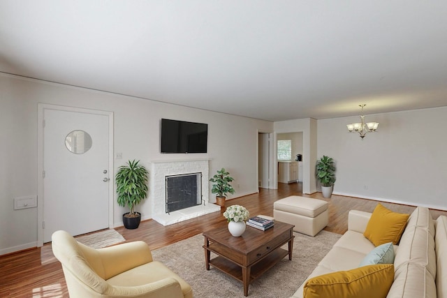 living room with a notable chandelier, a fireplace, and light wood-type flooring