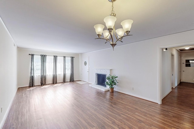 unfurnished living room with a notable chandelier, wood-type flooring, ornamental molding, and a brick fireplace