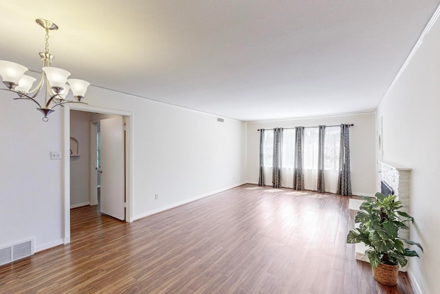 unfurnished living room featuring an inviting chandelier, ornamental molding, and hardwood / wood-style floors