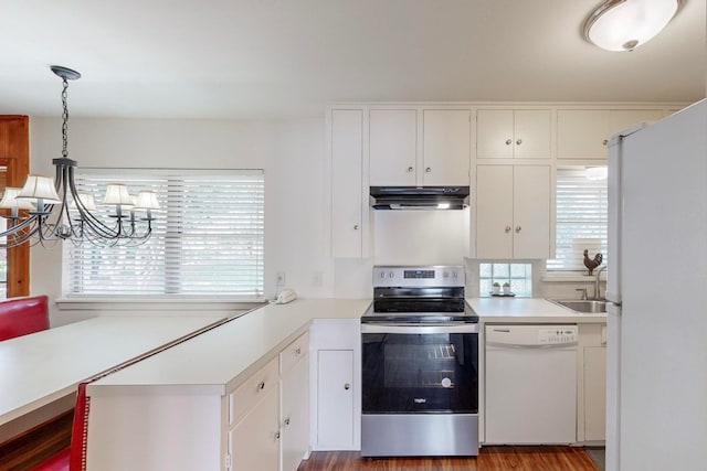 kitchen with white appliances, white cabinetry, and decorative light fixtures