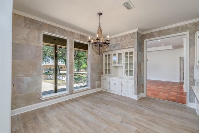 unfurnished dining area with crown molding, a chandelier, tile walls, and light wood-type flooring