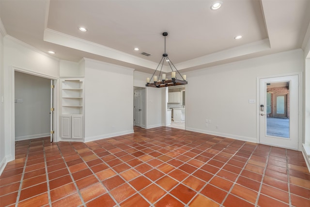 interior space with dark tile patterned flooring, a raised ceiling, and ornamental molding