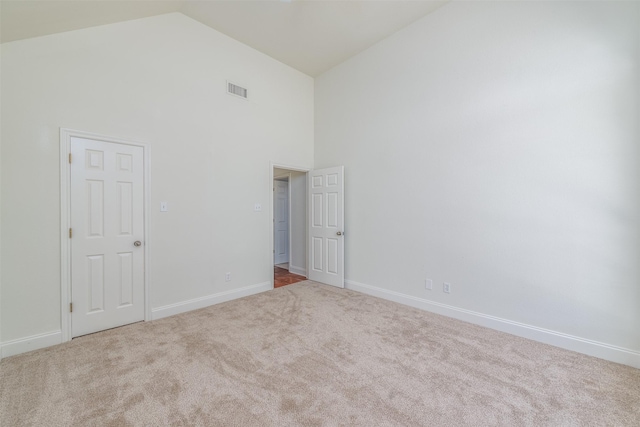 carpeted spare room with high vaulted ceiling