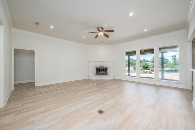 unfurnished living room featuring light hardwood / wood-style floors, a brick fireplace, ceiling fan, and crown molding