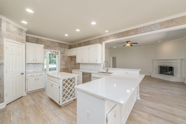 kitchen featuring light wood-type flooring, ceiling fan, sink, white cabinets, and a center island