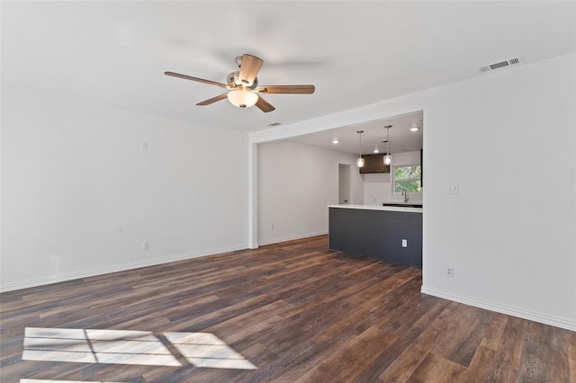 unfurnished living room featuring ceiling fan, dark hardwood / wood-style flooring, and sink