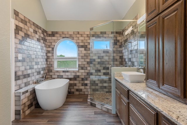 bathroom with vanity, separate shower and tub, wood-type flooring, tile walls, and lofted ceiling