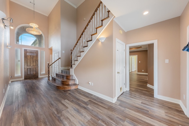 entryway with a high ceiling, hardwood / wood-style flooring, and crown molding