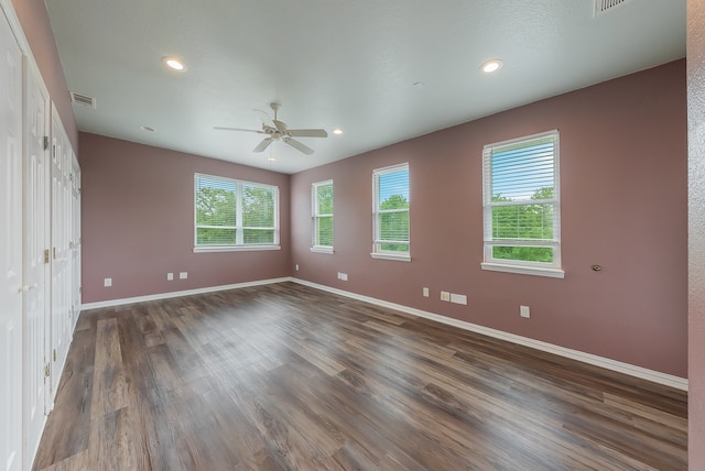 unfurnished bedroom featuring dark hardwood / wood-style floors, multiple windows, and ceiling fan