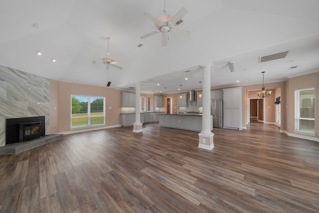 unfurnished living room featuring ornamental molding, ceiling fan with notable chandelier, a tile fireplace, high vaulted ceiling, and dark hardwood / wood-style floors