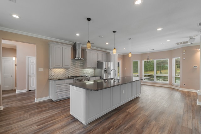 kitchen with appliances with stainless steel finishes, wall chimney exhaust hood, gray cabinets, dark hardwood / wood-style floors, and an island with sink