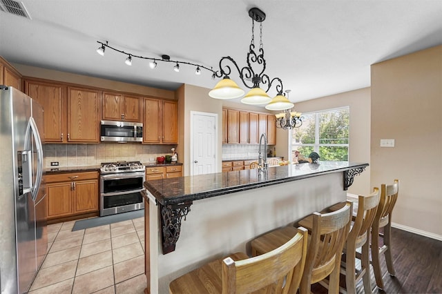 kitchen featuring backsplash, an inviting chandelier, decorative light fixtures, and appliances with stainless steel finishes