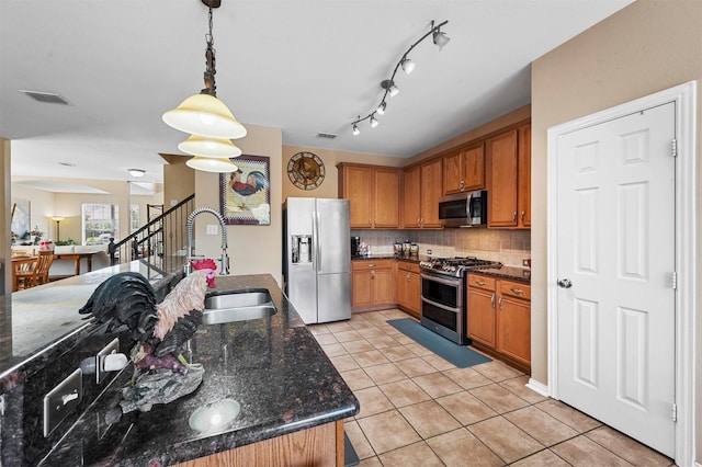 kitchen with dark stone counters, sink, tasteful backsplash, decorative light fixtures, and stainless steel appliances