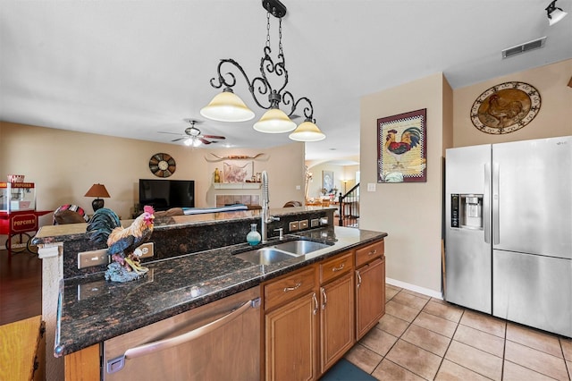 kitchen featuring appliances with stainless steel finishes, a kitchen island with sink, ceiling fan, sink, and decorative light fixtures