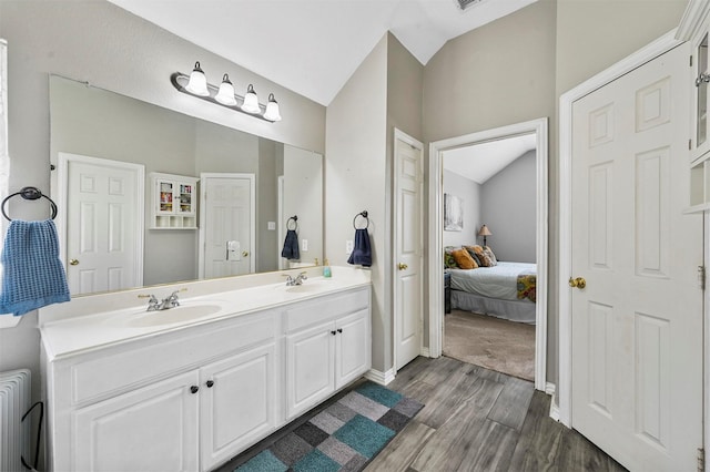 bathroom with radiator, vanity, wood-type flooring, and vaulted ceiling