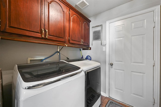 laundry area with tile patterned floors, washing machine and dryer, and cabinets