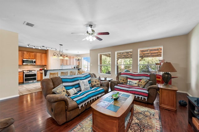 living room featuring hardwood / wood-style flooring, ceiling fan with notable chandelier, and rail lighting