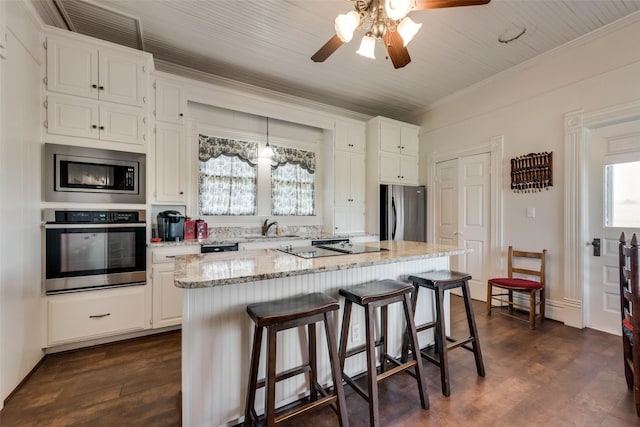 kitchen featuring white cabinetry, a center island, sink, stainless steel appliances, and light stone counters