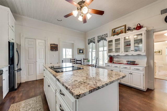 kitchen with white cabinets, a center island, black electric cooktop, and stainless steel refrigerator