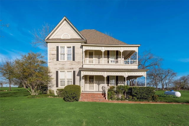 view of front facade featuring covered porch, a balcony, and a front lawn