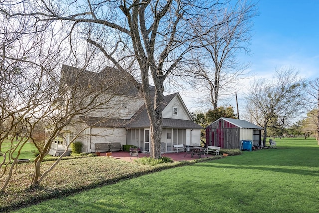 rear view of house featuring a patio, an outdoor structure, and a lawn