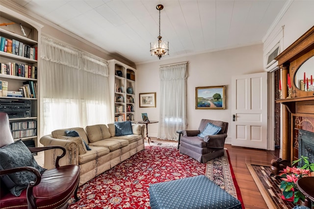 living room with crown molding, a fireplace, wood-type flooring, and an inviting chandelier