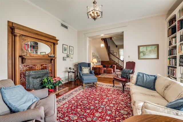 living room with a tile fireplace, crown molding, wood-type flooring, and a notable chandelier