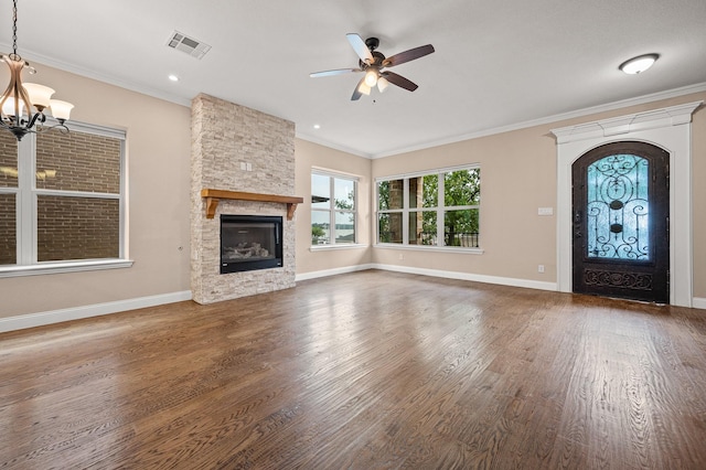 unfurnished living room featuring ceiling fan with notable chandelier, a stone fireplace, and ornamental molding