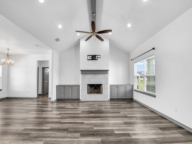 unfurnished living room with high vaulted ceiling, hardwood / wood-style floors, a tile fireplace, and ceiling fan with notable chandelier