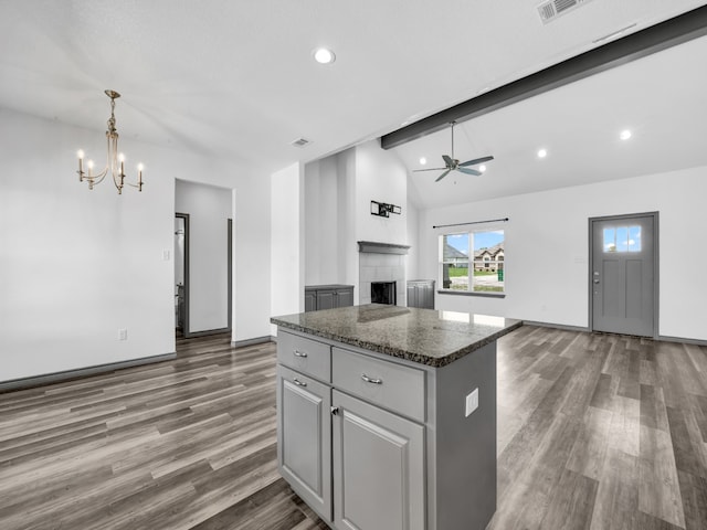 kitchen featuring beamed ceiling, a center island, dark hardwood / wood-style floors, and ceiling fan with notable chandelier