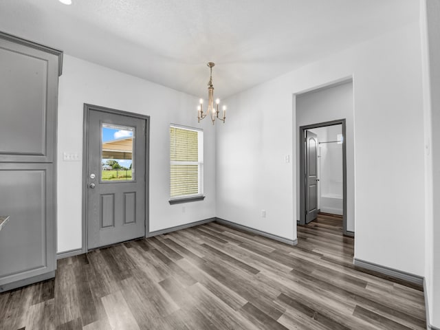 unfurnished dining area with a notable chandelier and hardwood / wood-style flooring