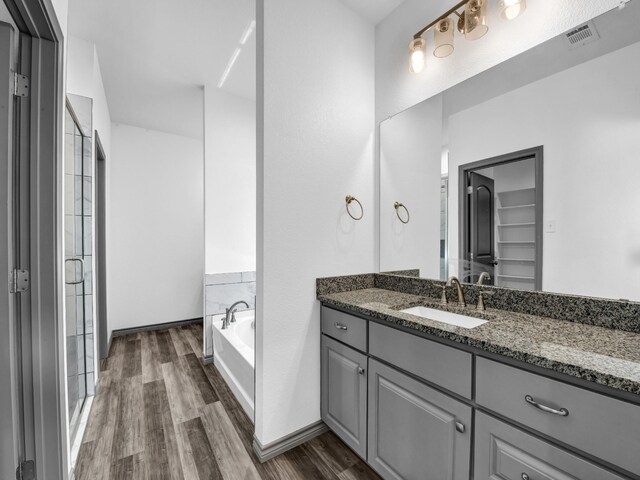 bathroom with wood-type flooring, vanity, and shower with separate bathtub