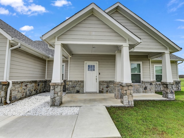 view of exterior entry featuring a porch and a yard