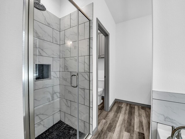 bathroom with walk in shower, toilet, and hardwood / wood-style flooring