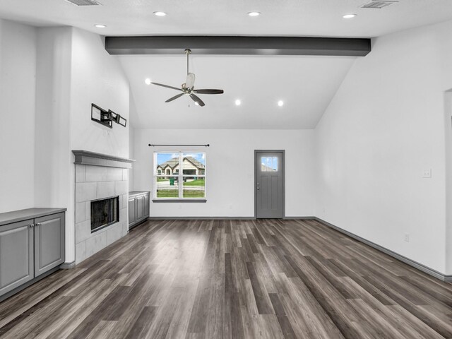 unfurnished living room with ceiling fan, beam ceiling, dark hardwood / wood-style flooring, a tile fireplace, and high vaulted ceiling