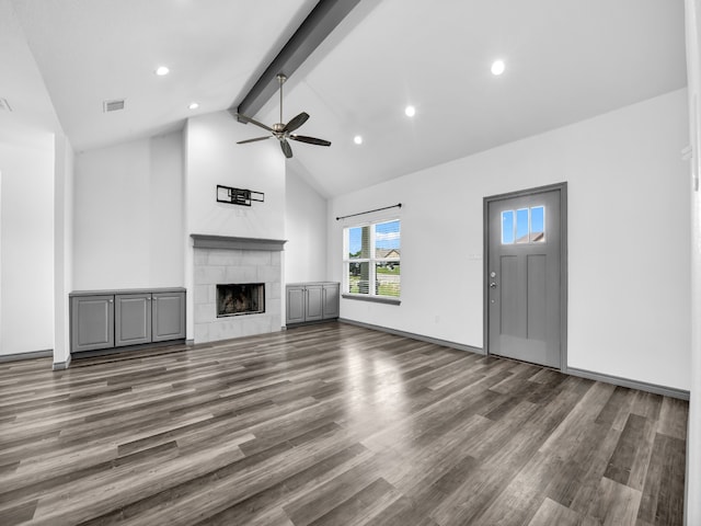 unfurnished living room featuring dark hardwood / wood-style flooring, ceiling fan, beam ceiling, high vaulted ceiling, and a tile fireplace