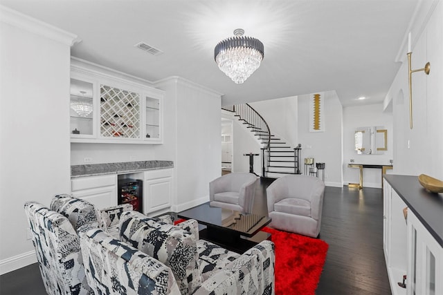 living room with wine cooler, dark hardwood / wood-style floors, ornamental molding, bar, and a notable chandelier