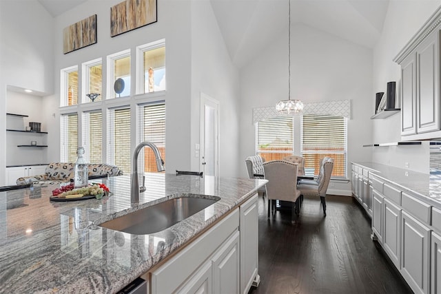 kitchen featuring a sink, a chandelier, high vaulted ceiling, dark wood-type flooring, and hanging light fixtures