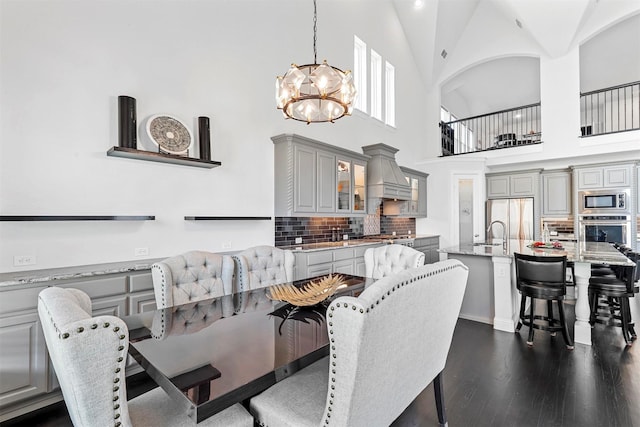 dining area with an inviting chandelier, high vaulted ceiling, and dark wood finished floors
