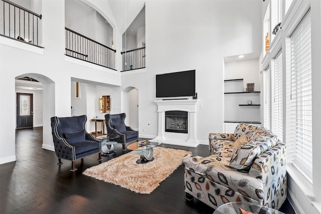 living room with dark wood-type flooring and a high ceiling