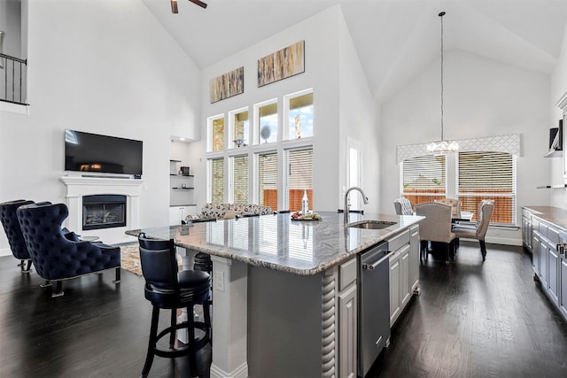 kitchen featuring a kitchen island with sink, high vaulted ceiling, sink, stainless steel dishwasher, and dark hardwood / wood-style floors