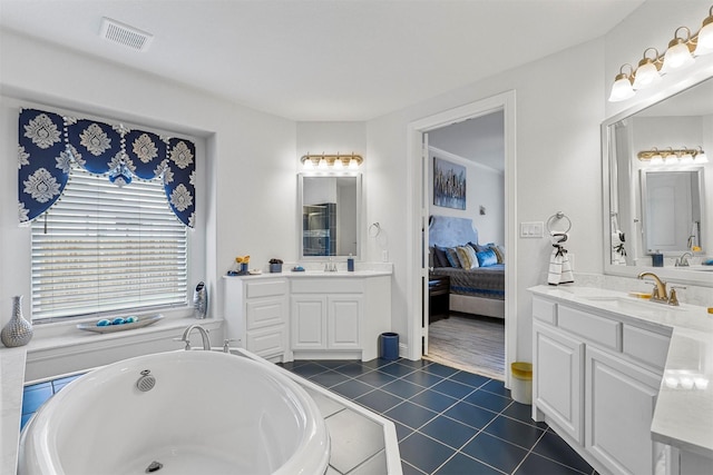 ensuite bathroom featuring tile patterned flooring, a freestanding tub, a sink, and visible vents