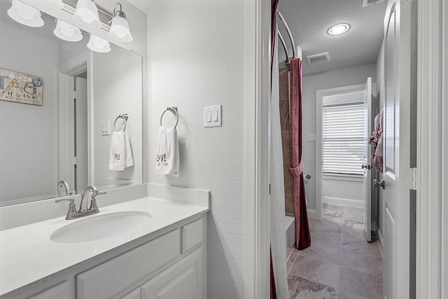 full bathroom with shower / tub combo, vanity, a textured ceiling, and visible vents
