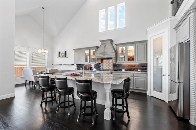 kitchen featuring stainless steel fridge, premium range hood, high vaulted ceiling, and gray cabinetry