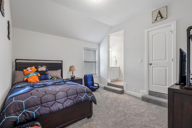 bedroom with ensuite bathroom, light carpet, and vaulted ceiling