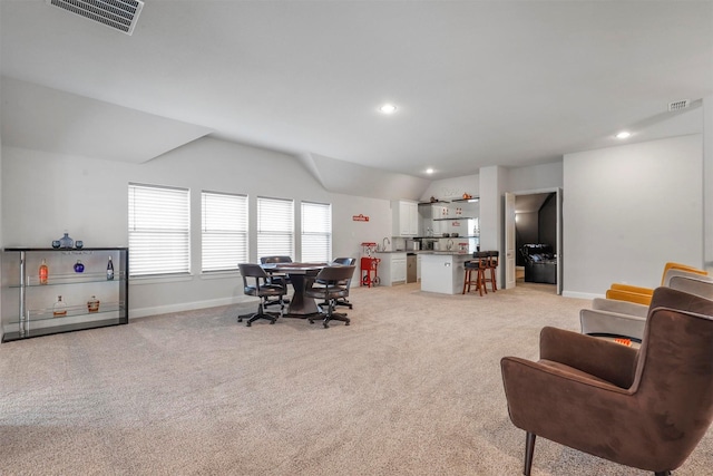 living area with lofted ceiling, light carpet, baseboards, and visible vents